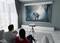 Mężczyzna i kobieta oglądają film z elephantem na dużym ekranie we współczesnym salonie.