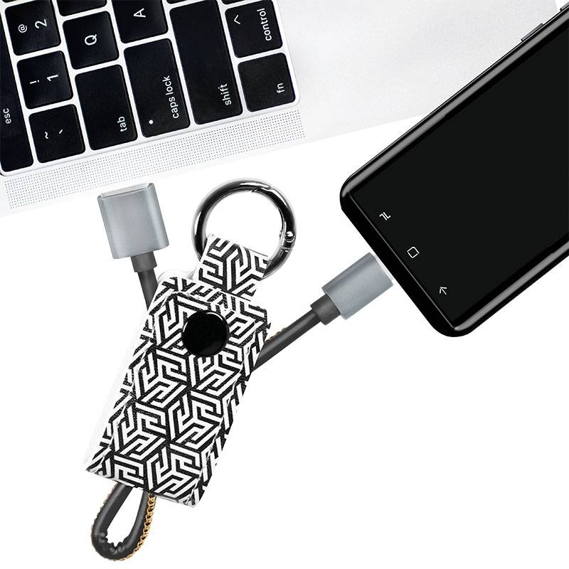 Smartfon jest podłączony do laptopa przez geometrycznie wzorzysty kabel ładujący.