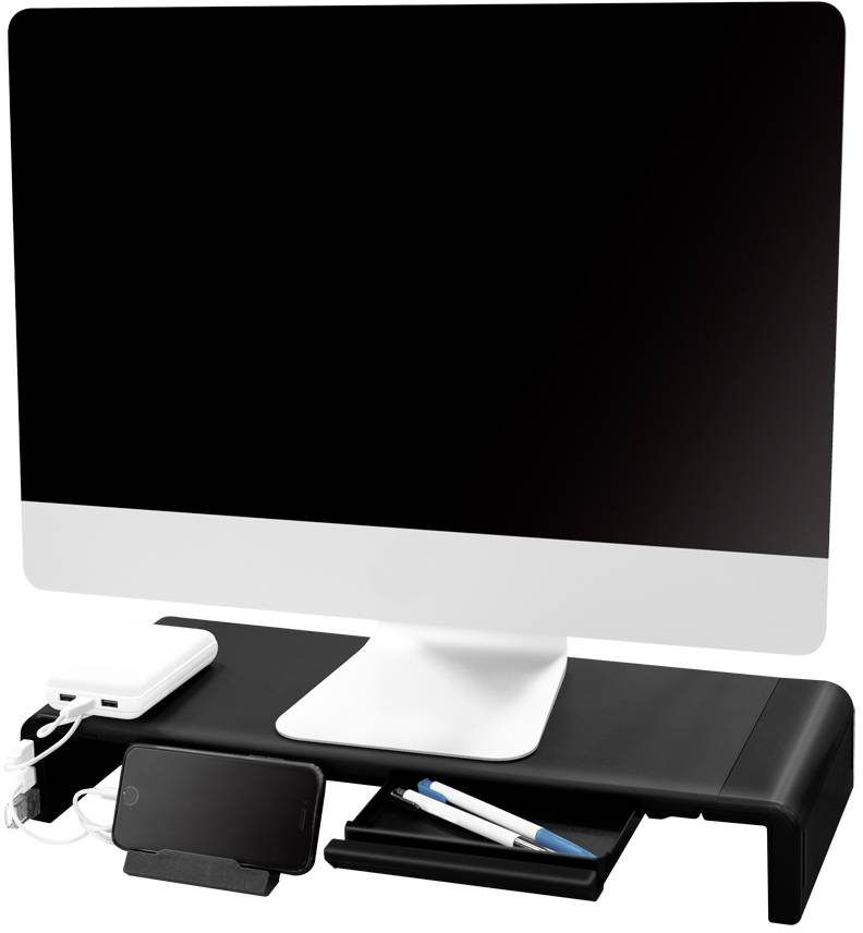 Ekran komputerowy na czarnym stojaku do monitora, pod którym znajdują się ładowarki, telefon komórkowy i długopisy.