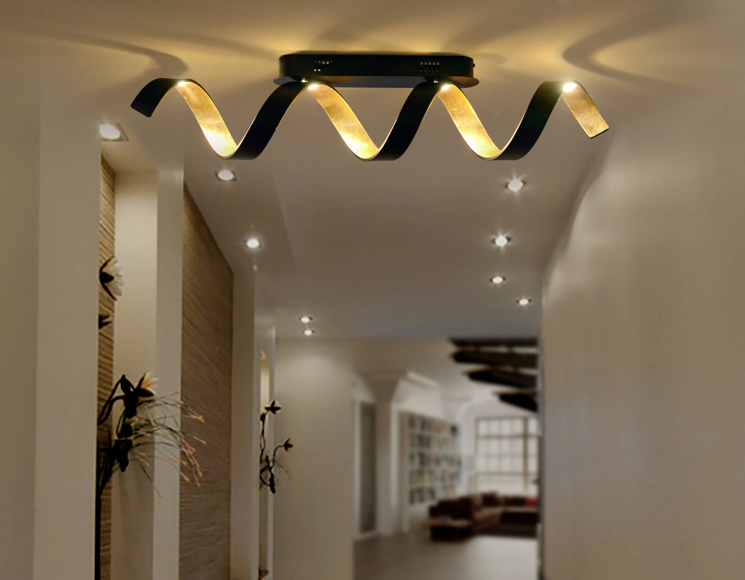 Nowoczesna lampa sufitowa o falistym designie emituje ciepłe światło. Lampa jest zamocowana na białym suficie.