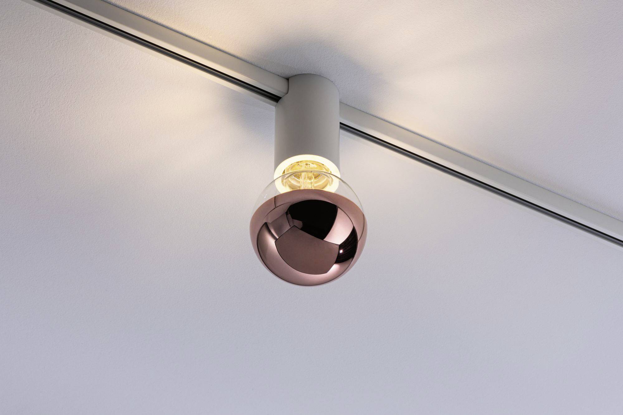 Nowoczesna lampa sufitowa z okrągłym, miedzianym kloszem rozświetla pomieszczenie.