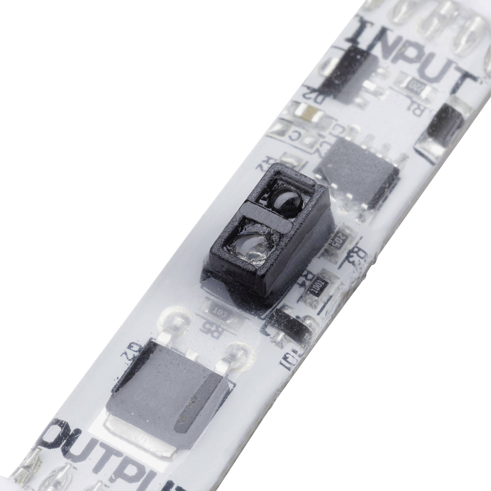 Zbliżenie płytki drukowanej paska LED z elementami elektronicznymi, widoczny napis INPUT i OUTPUT. Główna płytka w kolorze białym.