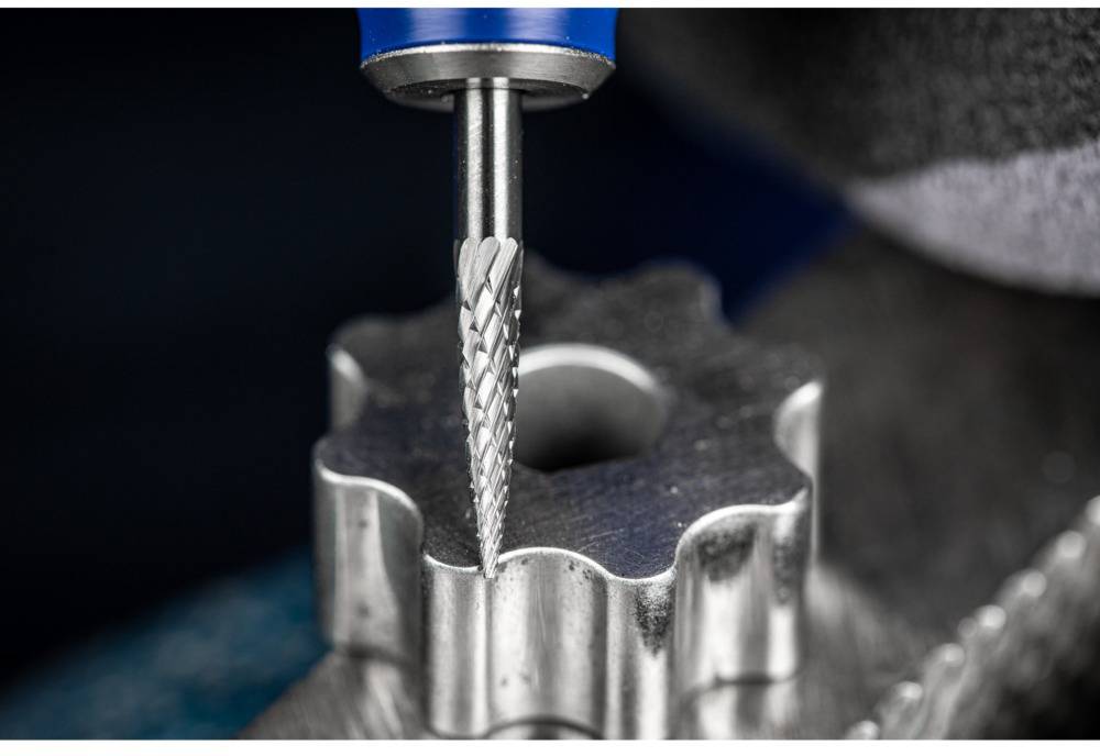 Frez precyzyjnie nacina kawałek metalu w kształcie zębów. Szczegółowe ujęcie z bliska procesu obróbki.