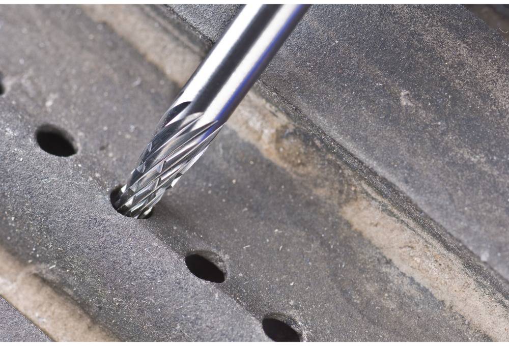 Zbliżenie wiertła wykonującego otwór w kawałku metalu.