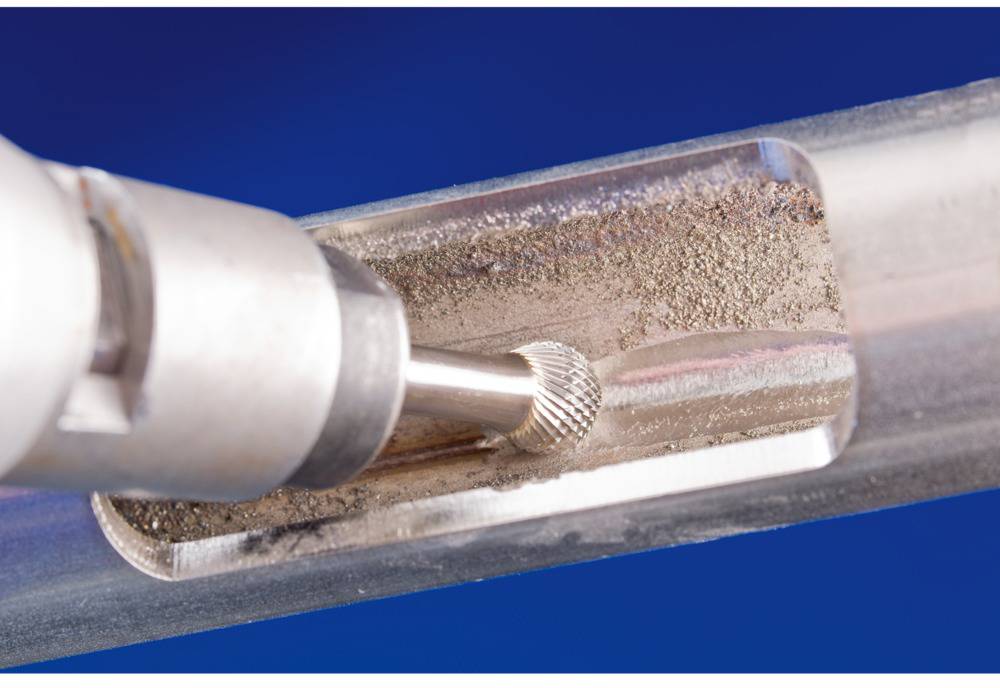 Frezarka metalowa obrabia okrągły element metalowy. Frez wytwarza wióry i nadaje powierzchni gładką, obrobioną strukturę.