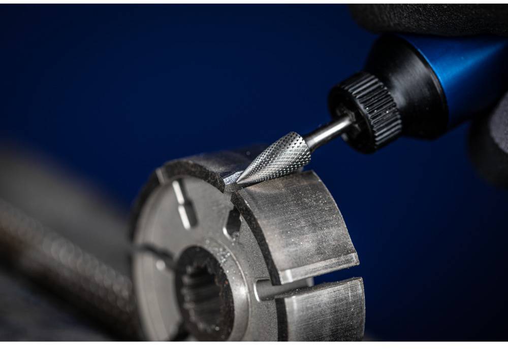 Metalowy wiertarz obrabia okrągły element metalowy z nacięciami w środowisku warsztatu. Zbliżenie ukazuje dokładność detalu.