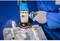 Osoba szlifuje powierzchnię metalową szlifierką kątową. Ma na sobie niebieskie ubranie robocze i rękawice ochronne.