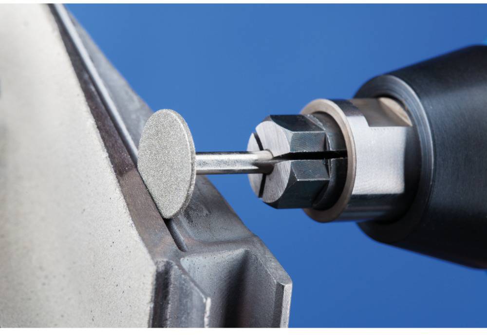 Zbliżenie narzędzia obrotowego polerującego metalową powierzchnię tarczą szlifierską. Narzędzie w ruchu, niebieskie tło.