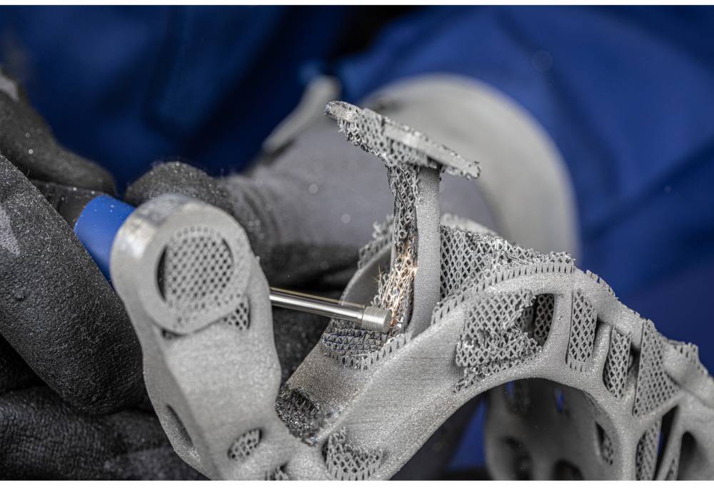 Zbliżenie osoby obrabiającej precyzyjne detale narzędziem na obiekcie wydrukowanym w technologii 3D.
