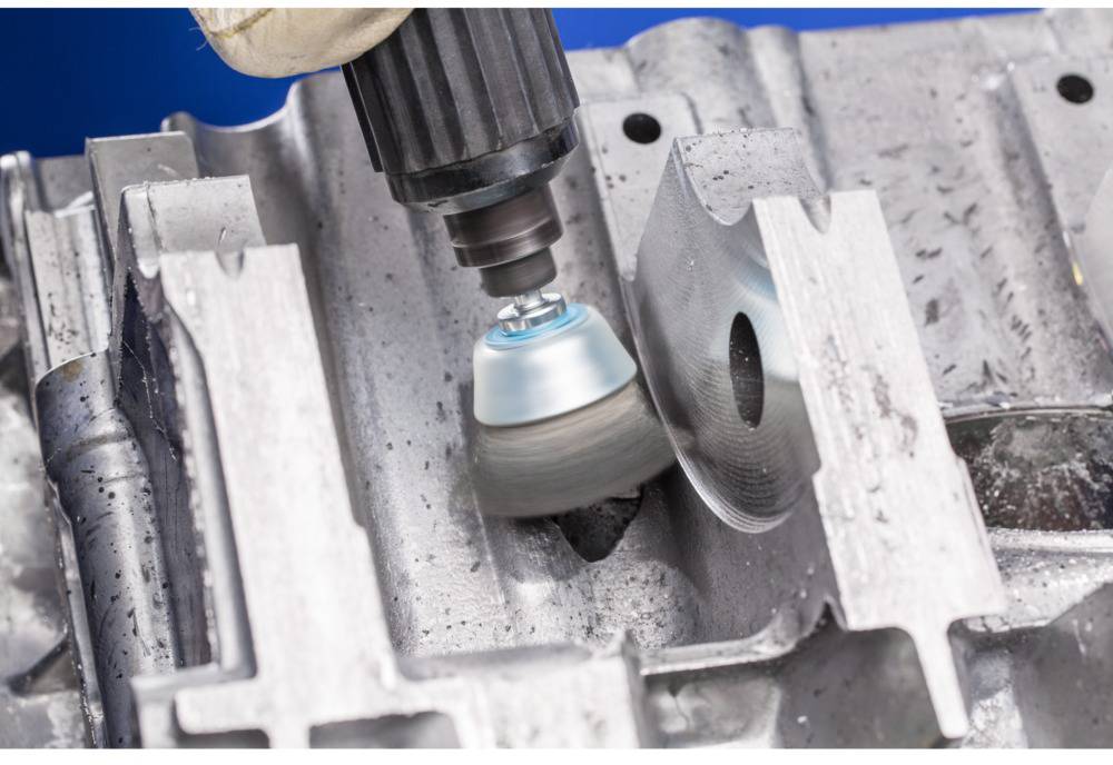 Narzędzie wiertnicze poleruje powierzchnię metalu, usuwając nierówności. Po lewej stronie jest gładka powierzchnia, po prawej stronie wciąż szorstka.