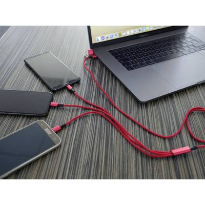 Laptop ładuje trzy smartfony czerwonymi kablami USB na ciemnym drewnianym stole.