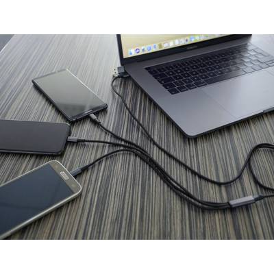 Laptop na stole, podłączony do trzech smartfonów za pomocą kabli USB. Wszystkie urządzenia są ładowane jednocześnie.