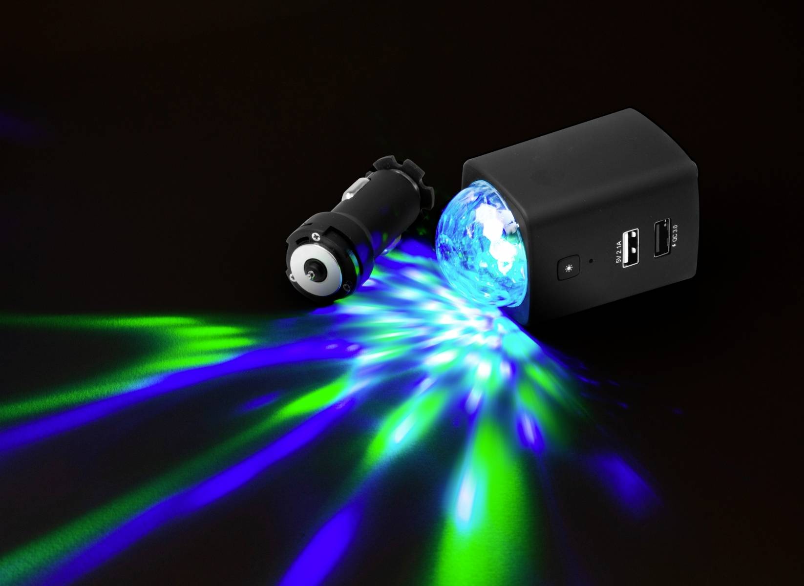 Przenośne urządzenie świetlne rzuca niebieskie i zielone wiązki światła w różnych kierunkach na ciemnym tle.