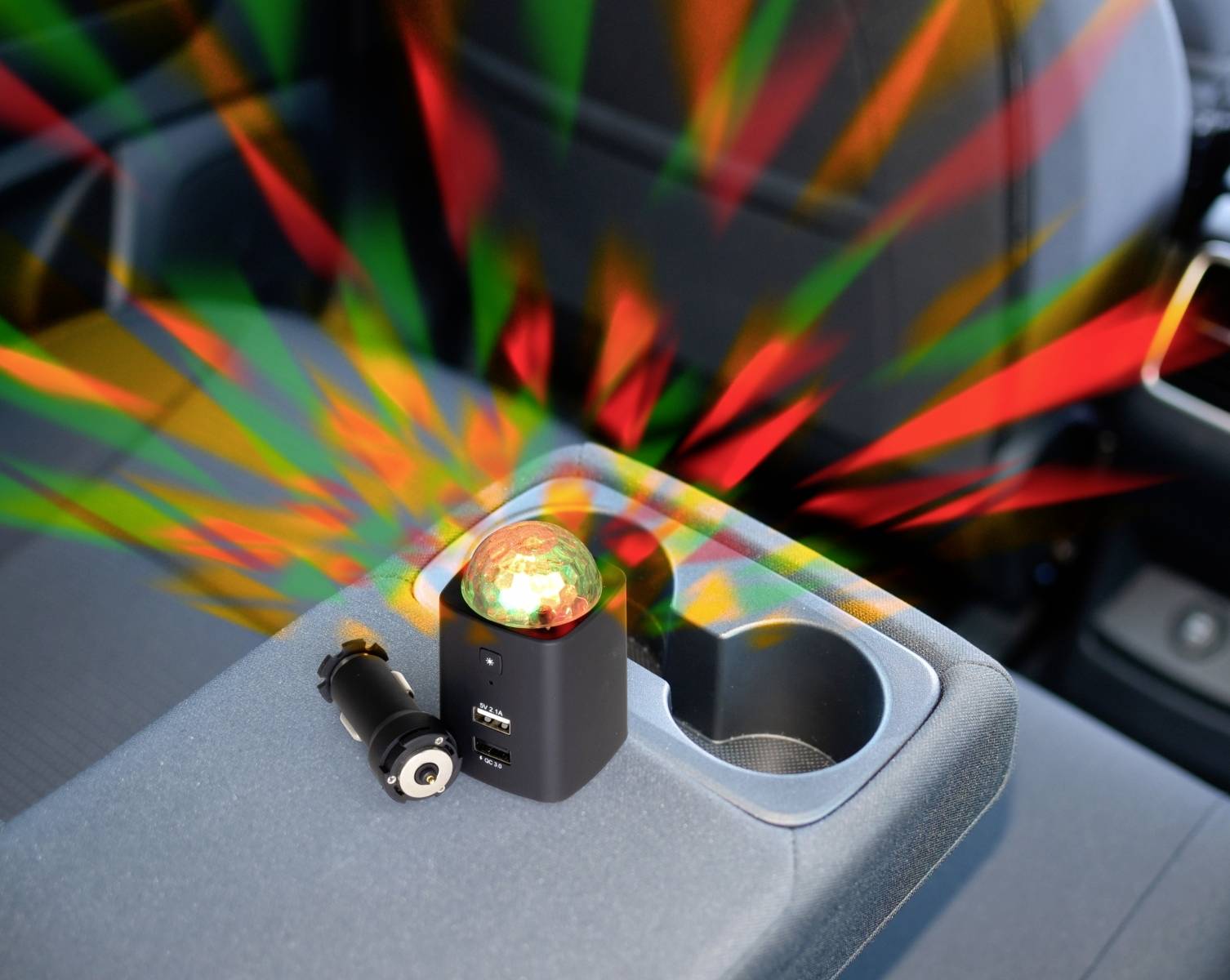 Mały projektor we wnętrzu samochodu rzuca czerwone i zielone światła, które rozchodzą się od konsoli środkowej.