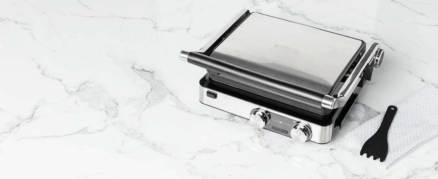 Grill elektryczny na powierzchni marmurowej z akcesoriami. Nowoczesny design, odpowiedni do grillowania w pomieszczeniach i łatwego czyszczenia.