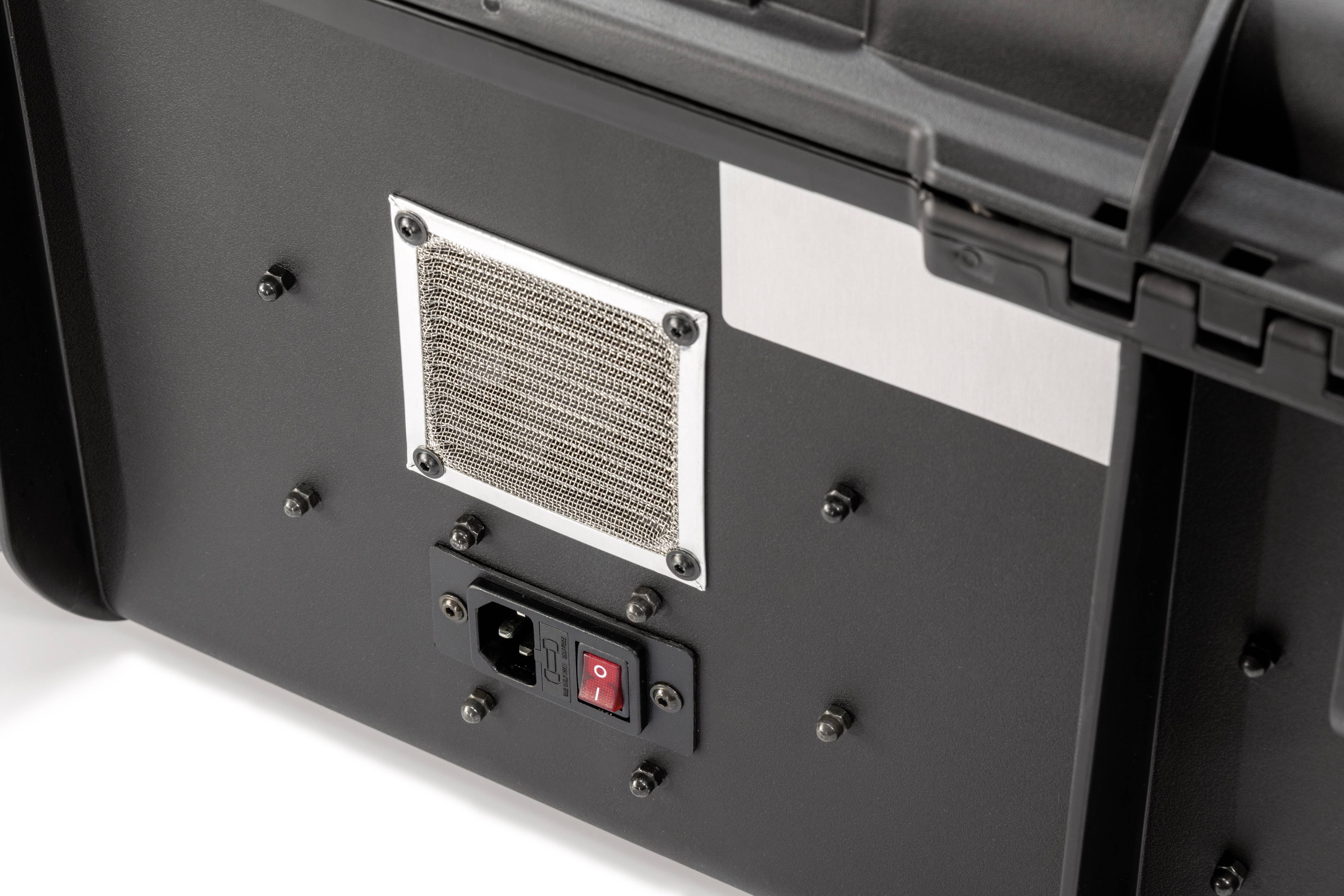 Szczegółowy widok tylnej części urządzenia technicznego, z kratką wentylacyjną oraz czerwonym przełącznikiem włączania/wyłączania umieszczonym poniżej gniazda elektrycznego.