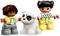Dwie uśmiechnięte postacie LEGO-Duplo, chłopiec i dziewczynka, bawią się białym psem w brązowe łaty. Wyglądają na bardzo radosne.