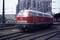 Czerwona lokomotywa Deutsche Bahn stoi na torach kolejowych, w tle widać katedrę.