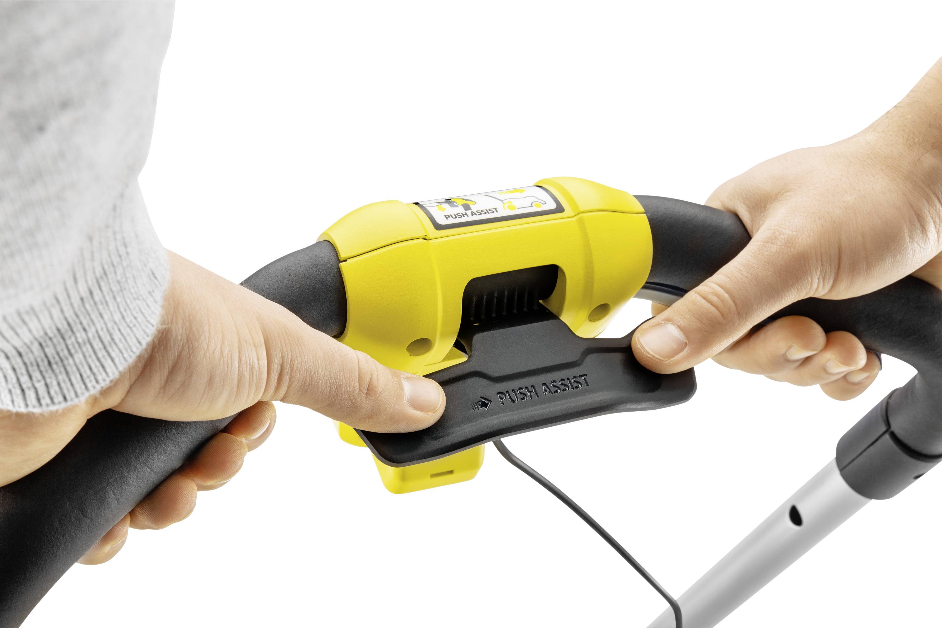 Zbliżenie dłoni trzymających uchwyt kosiarki. Żółta dźwignia bezpieczeństwa jest naciskana.