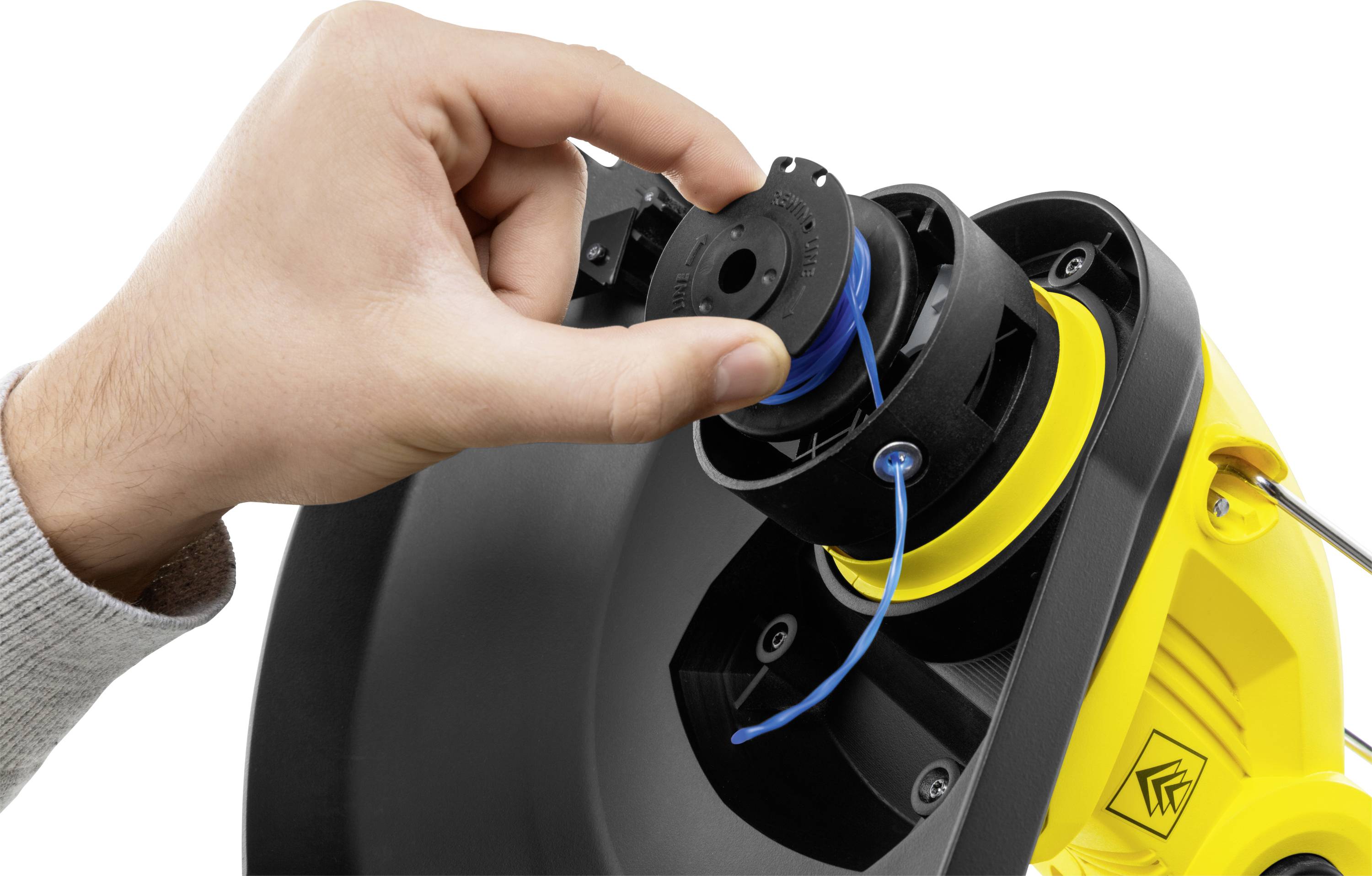 Ręka wymienia głowicę żyłkową żółtego kosa. Żyłka zostaje na nowo nawleczona.