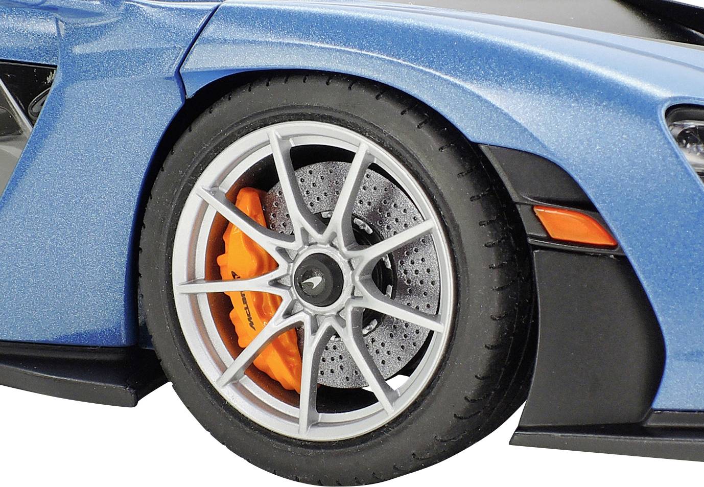 Zbliżenie niebieskiego samochodu ukazuje lewy przedni koło z pomarańczowym zaciskiem hamulcowym za srebrnym obręczem.