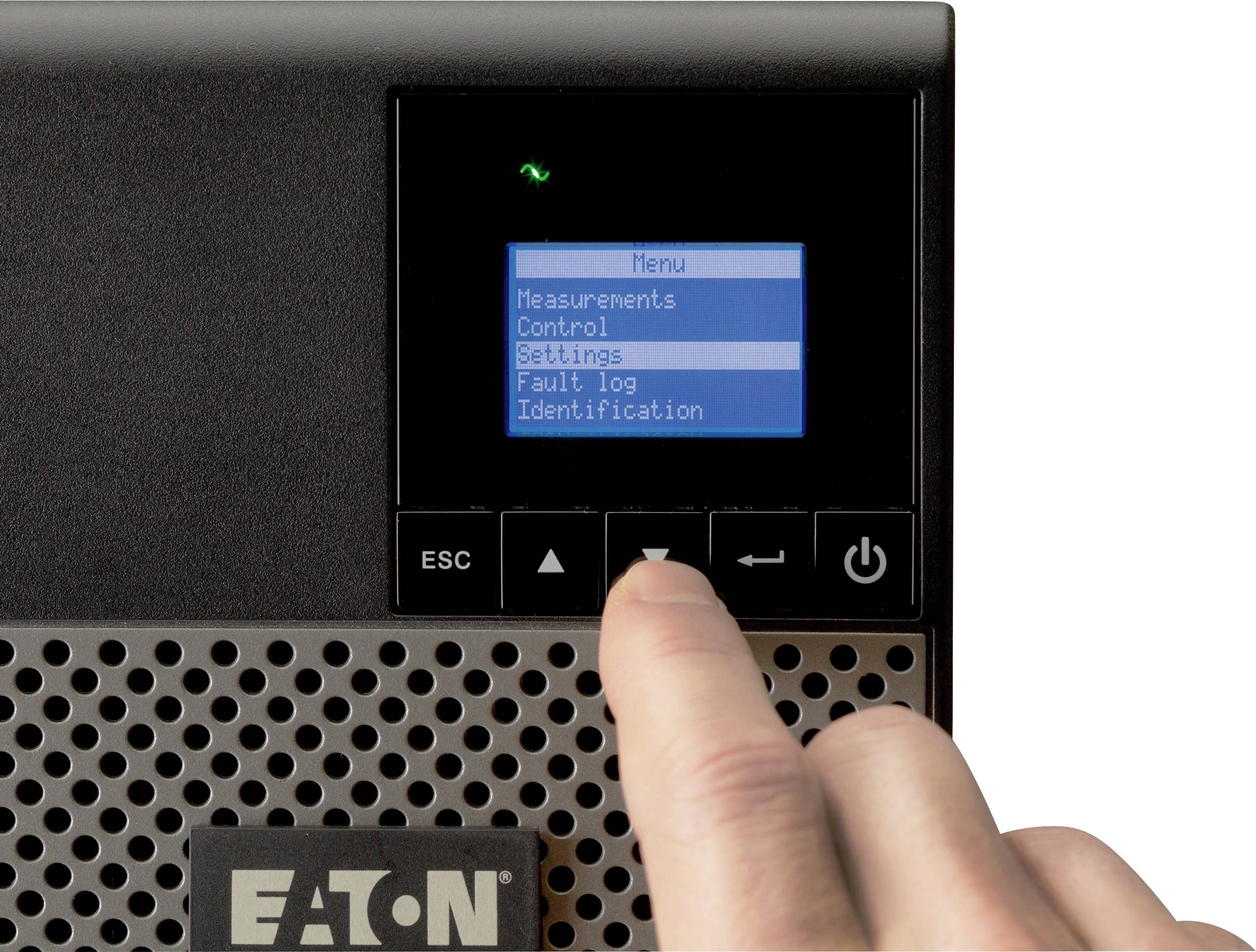 Jedna ręka naciska przycisk strzałki w dół na urządzeniu sterującym. Na ekranie widoczne jest menu z opcjami takimi jak 'Pomiary' i 'Sterowanie'.