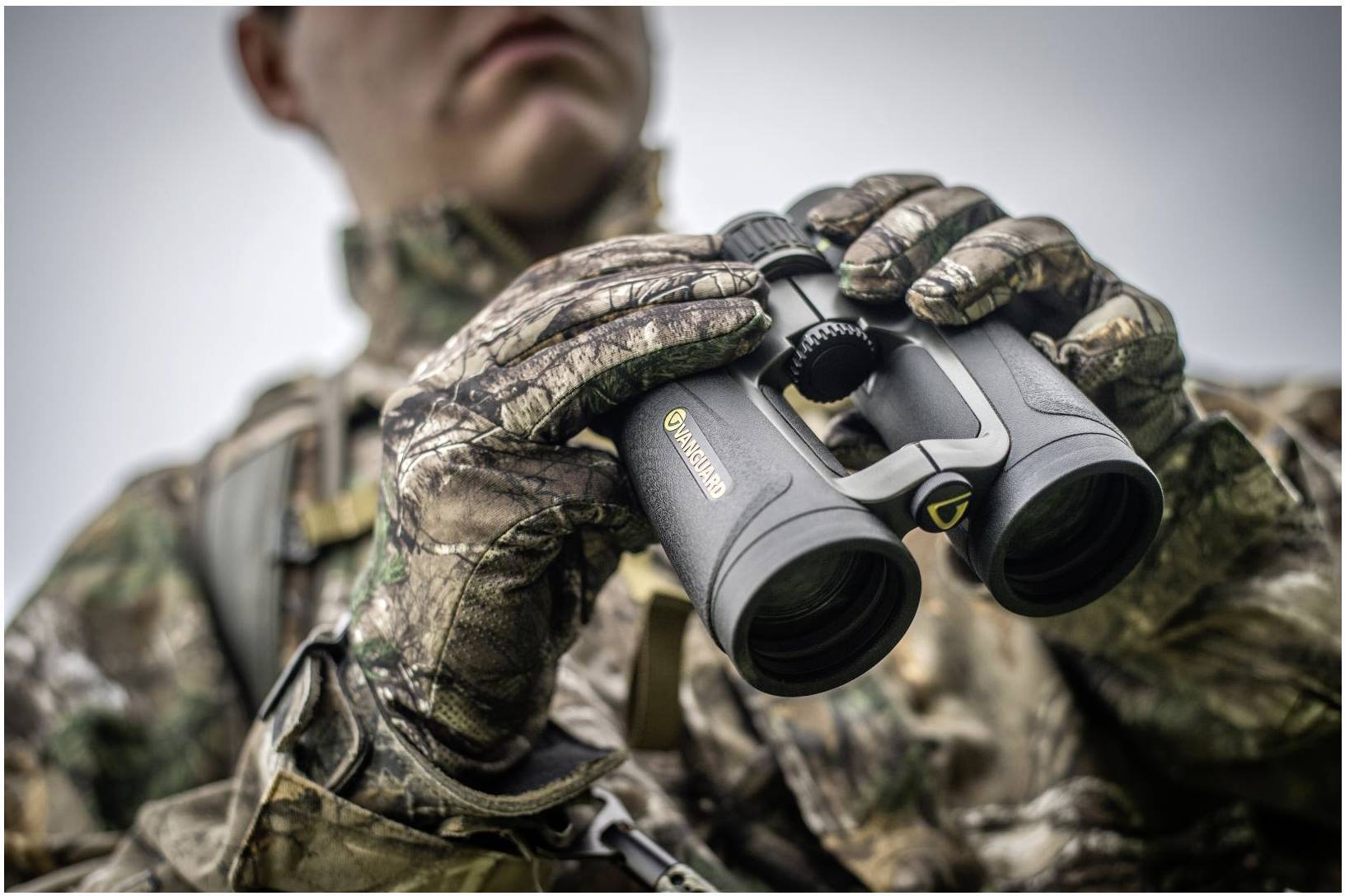 Osoba w kamuflażu trzyma lornetkę, gotowa do obserwacji przyrody.