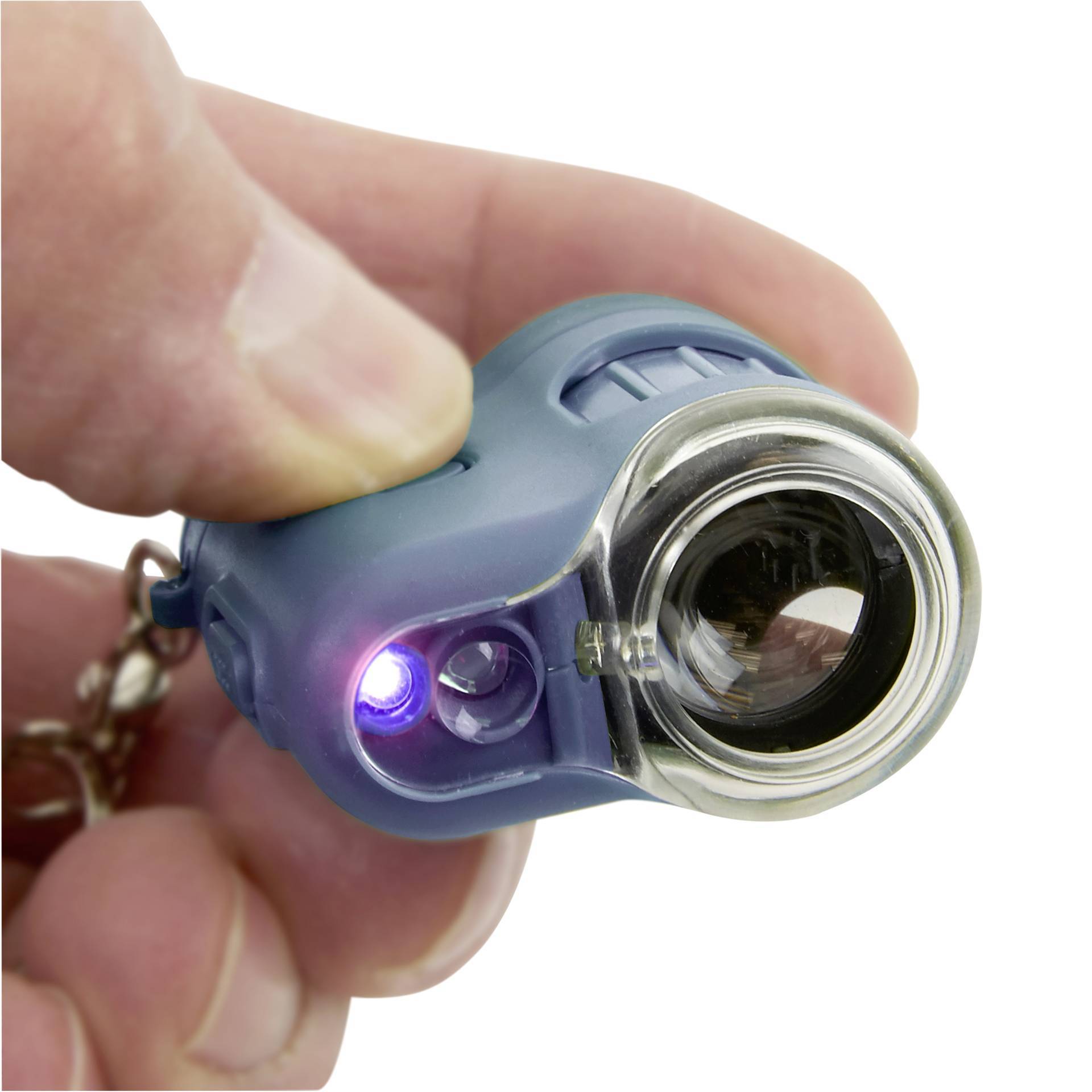 Kciuk i palec wskazujący trzymają małą latarkę w ręku. Latarka posiada soczewkę i świecącą diodę LED.