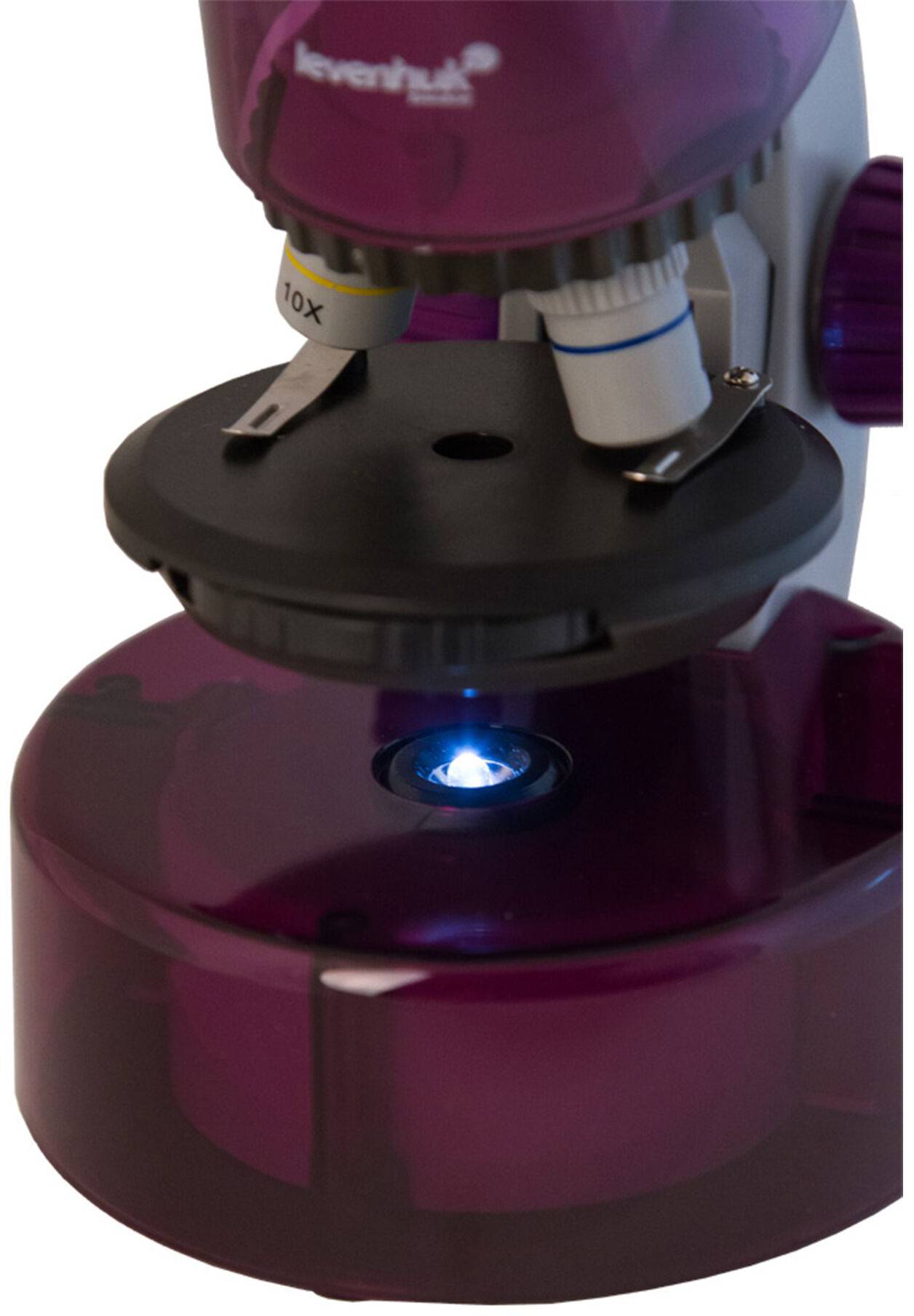 Fioletowy mikroskop koncentruje się obiektywem na próbce. Oświetlenie jest widoczne pod próbką.