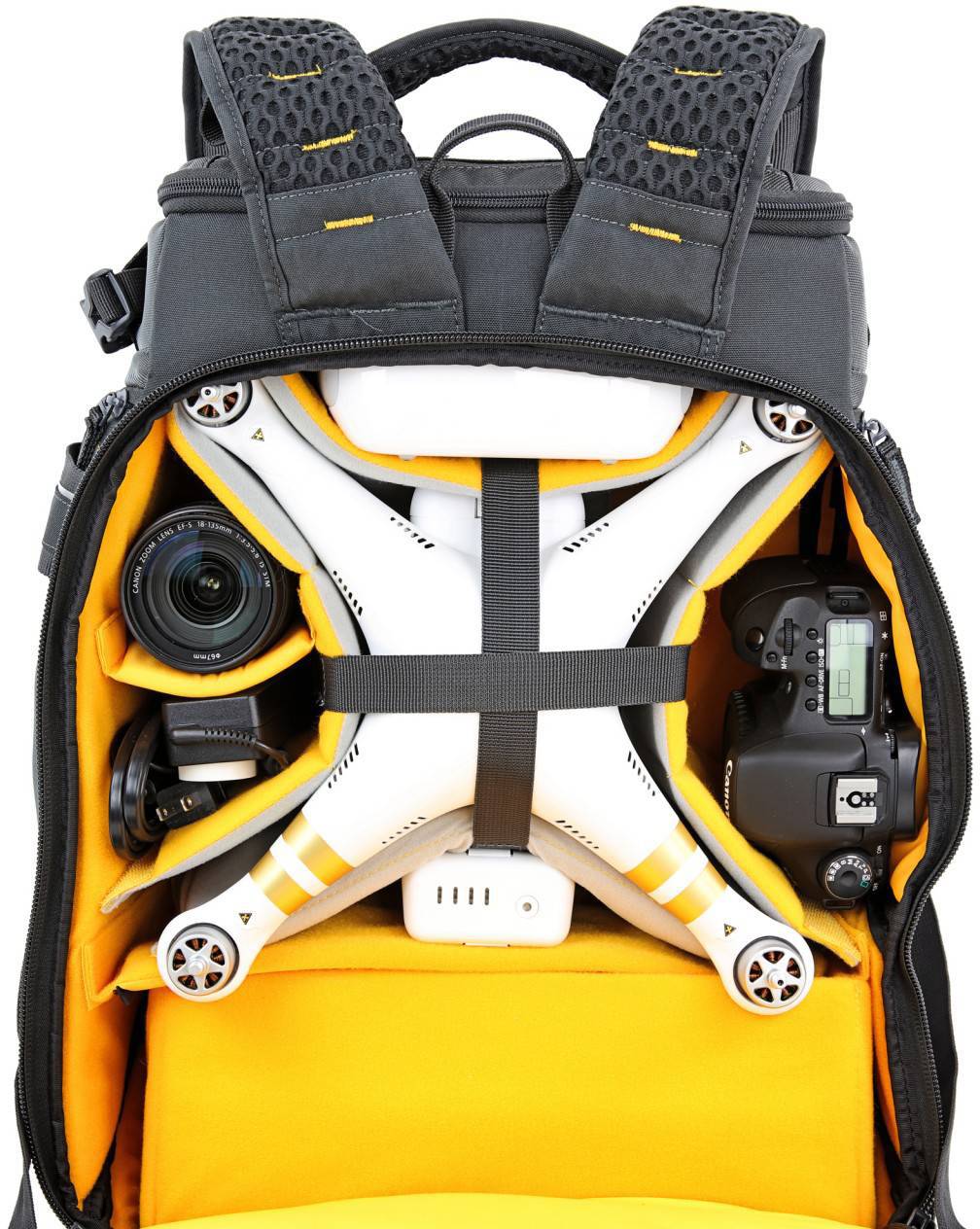 Otwarty plecak fotograficzny z dronem, aparatem i obiektywami w oddzielnych komorach.