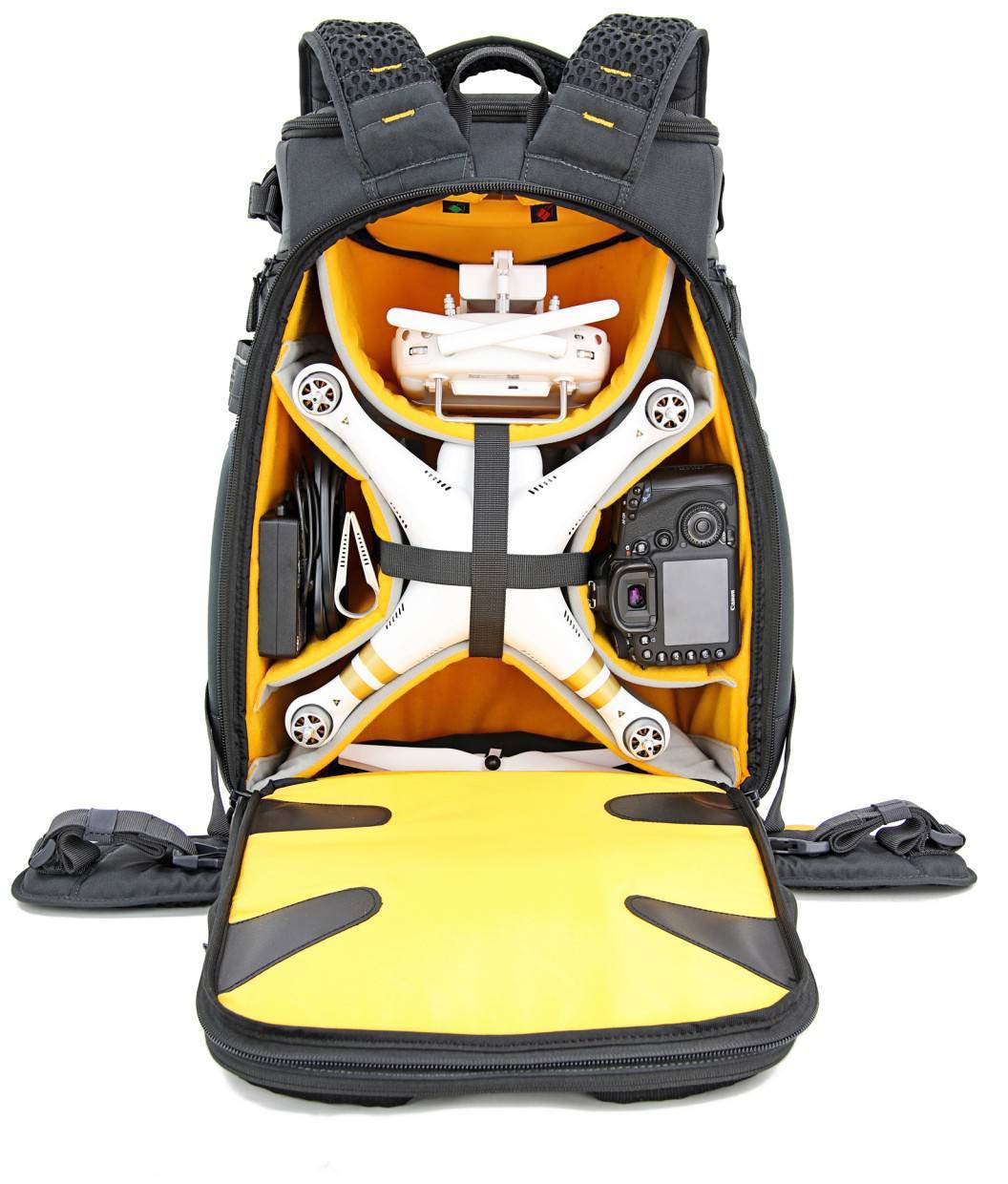 Otwarty plecak ukazuje uporządkowane wnętrze z dronem, kamerą i akcesoriami. Wewnętrzna wyściółka jest żółta.