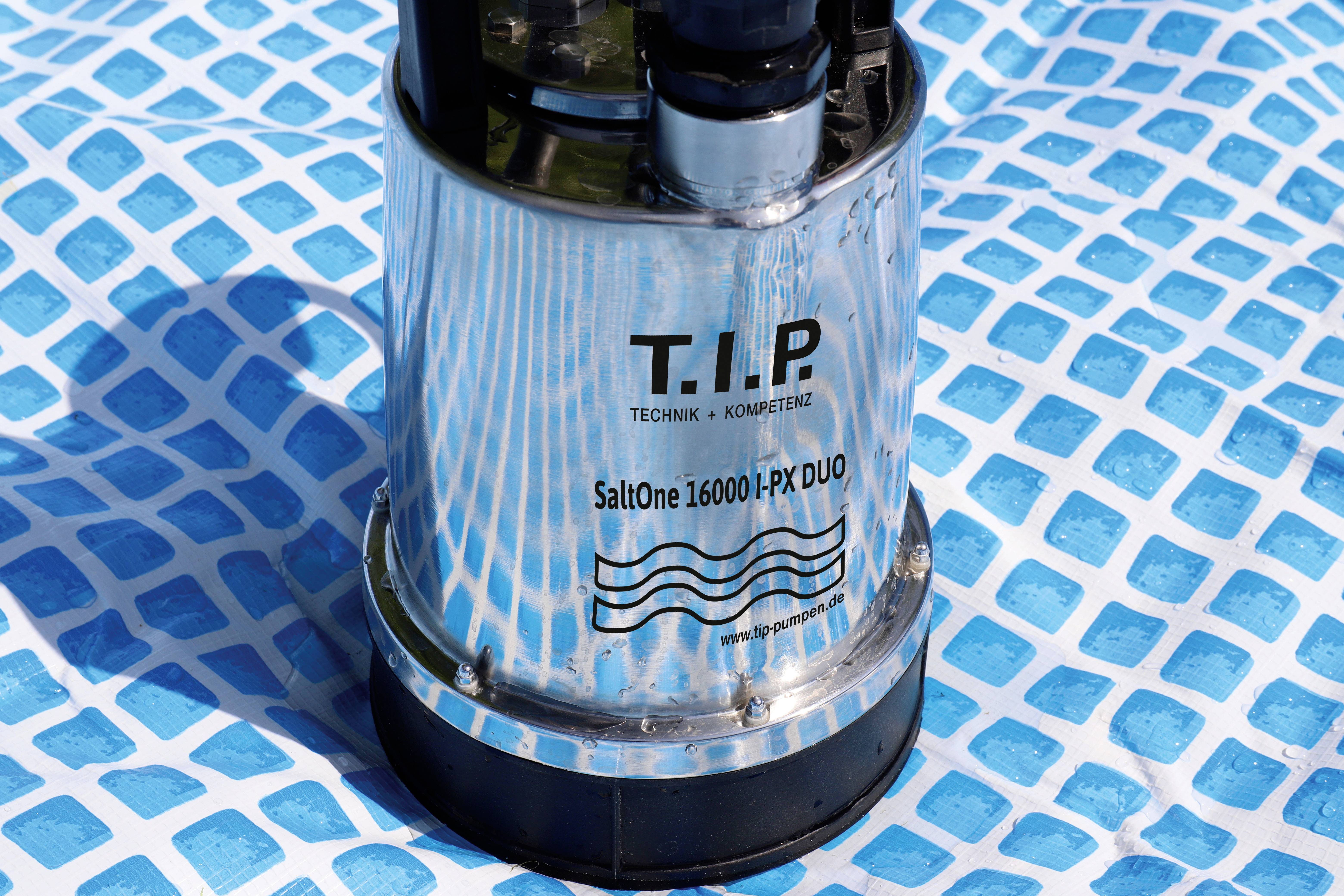 Srebrna pompa wodna z napisem 'T.I.P. SaltOne 16000 IPX DUO' stoi na niebiesko-białym wzorze mozaikowym.