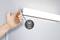 Dłoń włącza białą lampkę za pomocą bocznego przełącznika. Obok widnieje symbol 'white switch'.