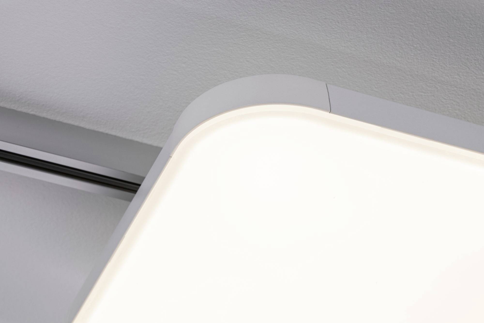 Nowoczesna, prostokątna lampa sufitowa o zaokrąglonych narożnikach, emitująca miękkie białe światło, zamontowana na szarym suficie.