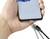 Dłoń trzyma smartfon z magnetycznym złączem ładowania. Kabel ładujący z magnetyczną końcówką zbliża się do złącza.