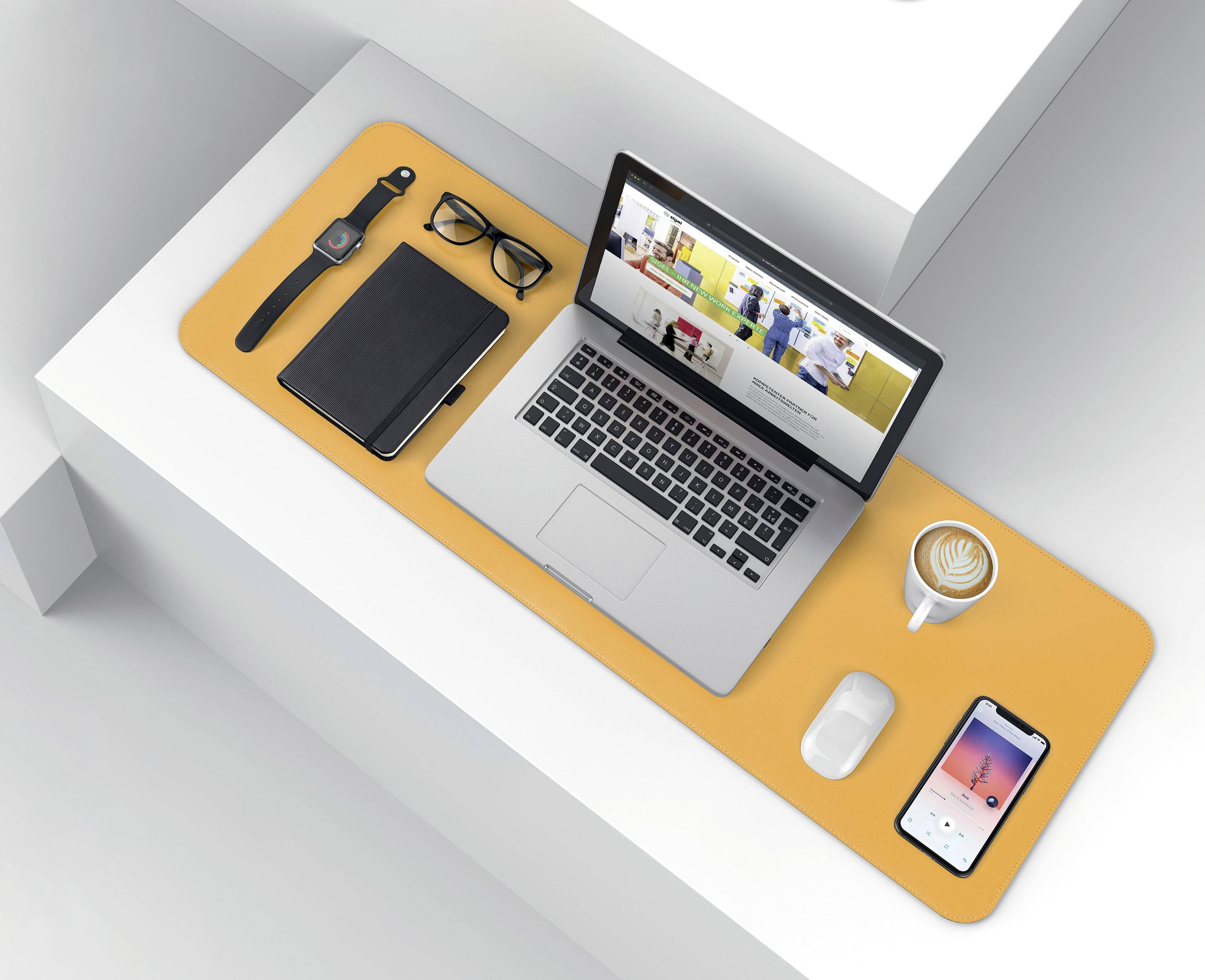 Laptop z otwartą stroną internetową, filiżanka cappuccino, smartwatch, okulary, notes i smartfon na stole.