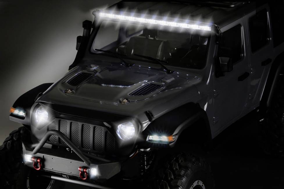 Terenówka z podświetloną diodową belką świetlną na dachu i włączonymi reflektorami, stojąca przy słabym oświetleniu.