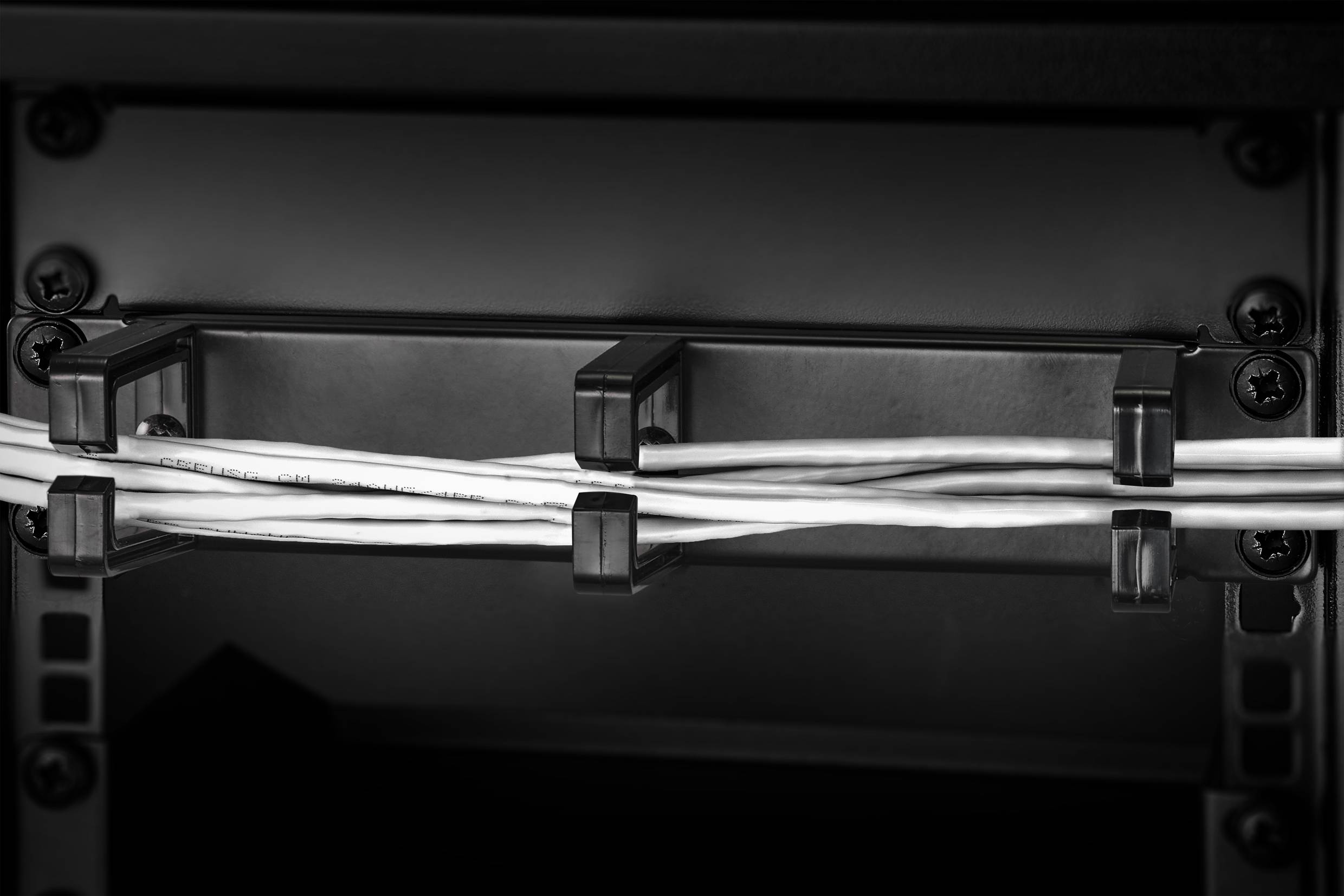 Kable są starannie zorganizowane za pomocą uchwytów i biegną poziomo w ciemnej, strukturalnej ramie.