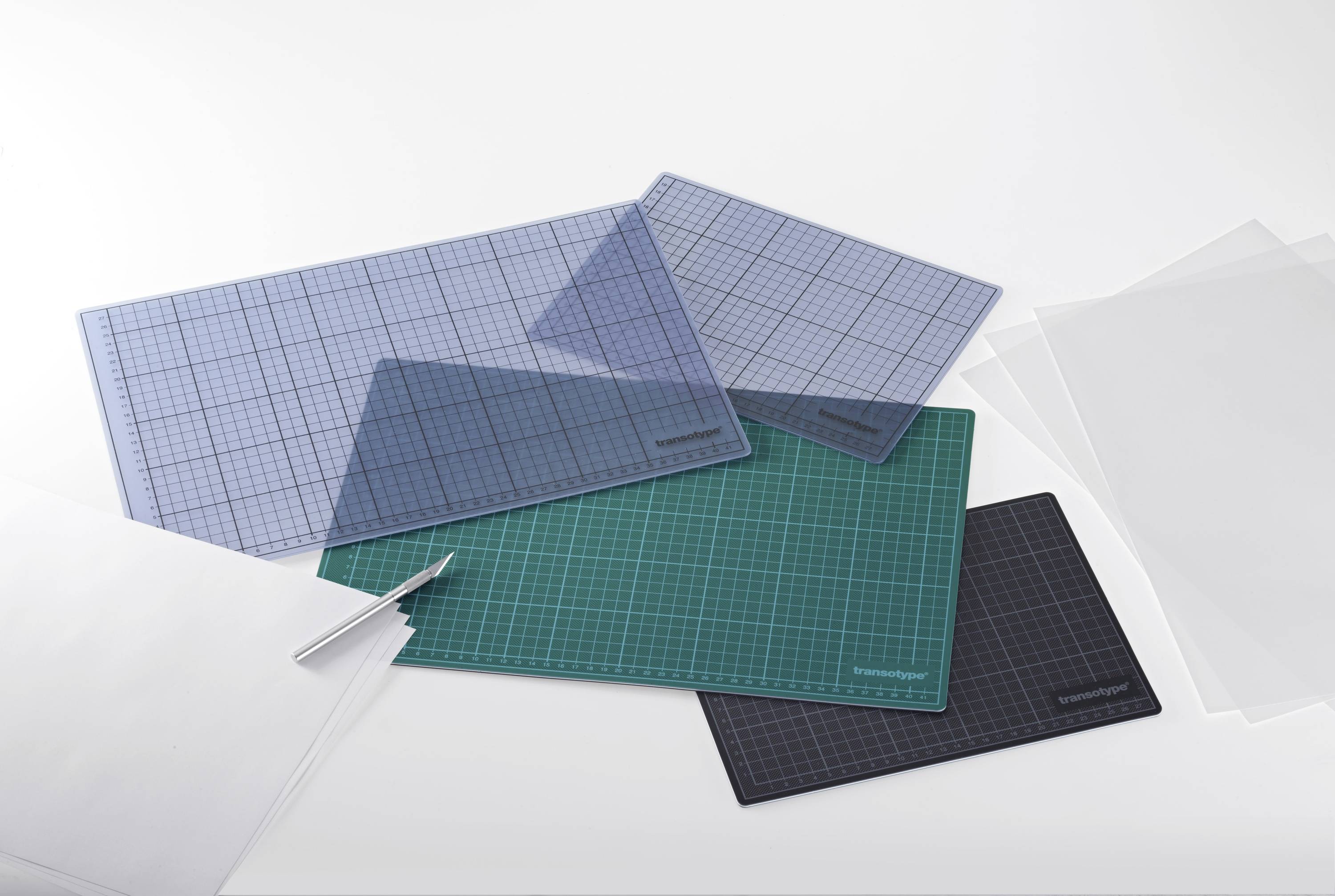 Kilka desek do krojenia w różnych kolorach i rozmiarach leży jedna na drugiej na stole. Obok nich leży nóż do krojenia.