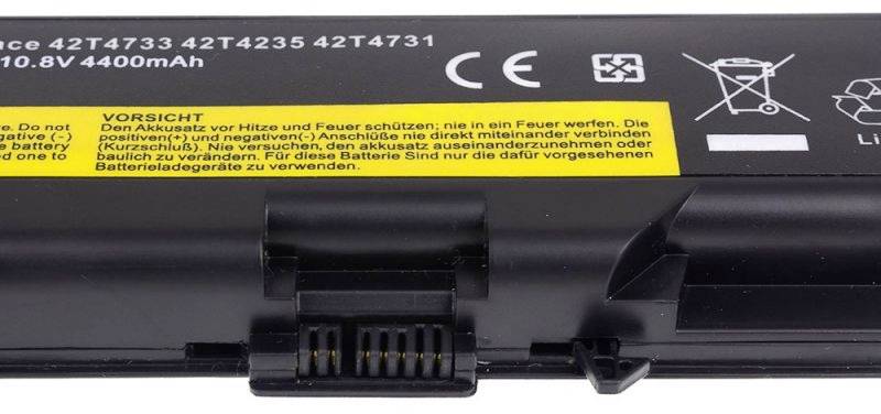 Czarny akumulator laptopa z żółtą naklejką ostrzegawczą: 'UWAGA: Chronić baterię przed gorącem i ogniem; nigdy nie wrzucać do ognia.'