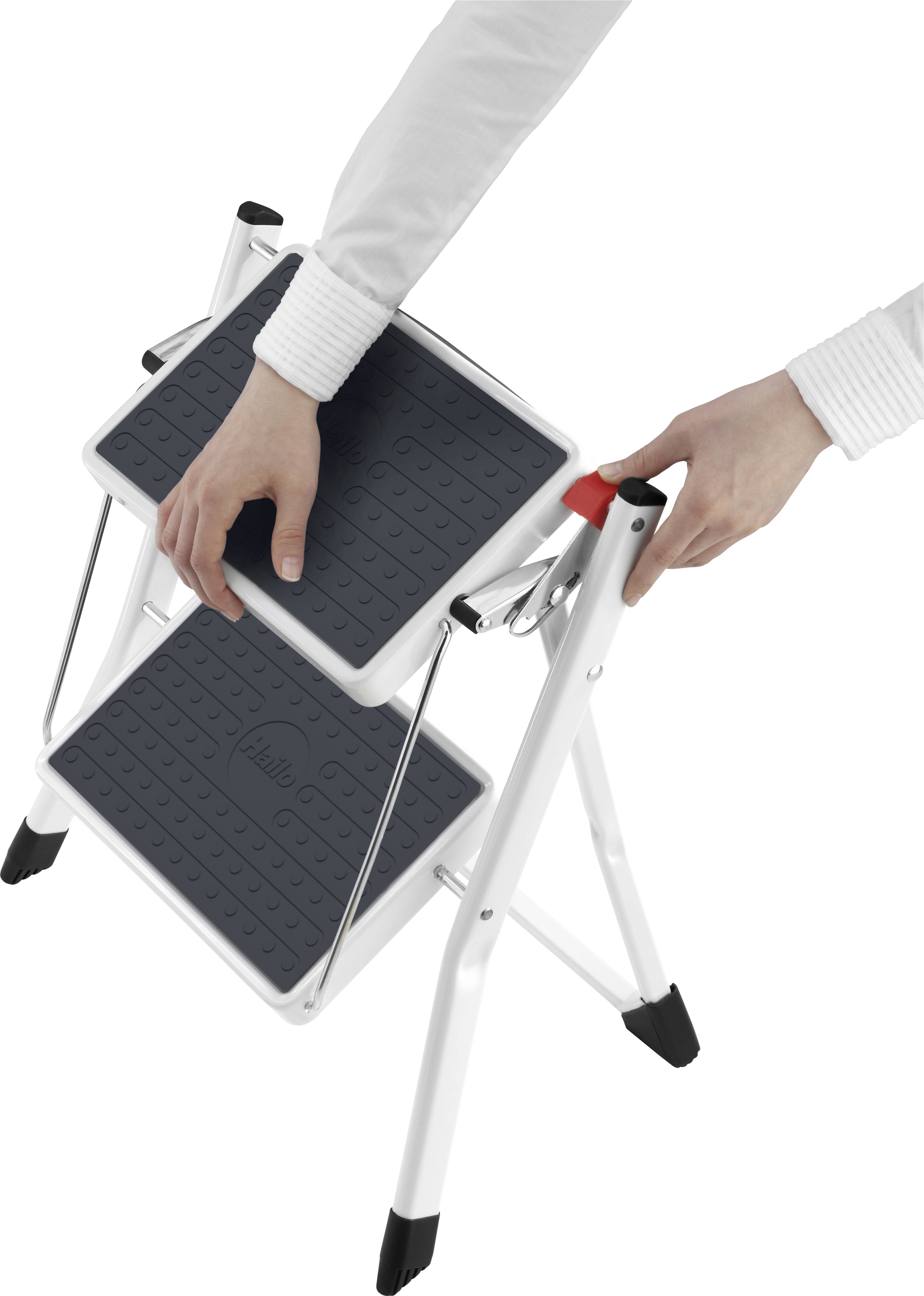 Osoba trzyma białą drabinę składaną z czarnymi stopniami i czerwonym uchwytem, gotową do użycia lub złożenia.