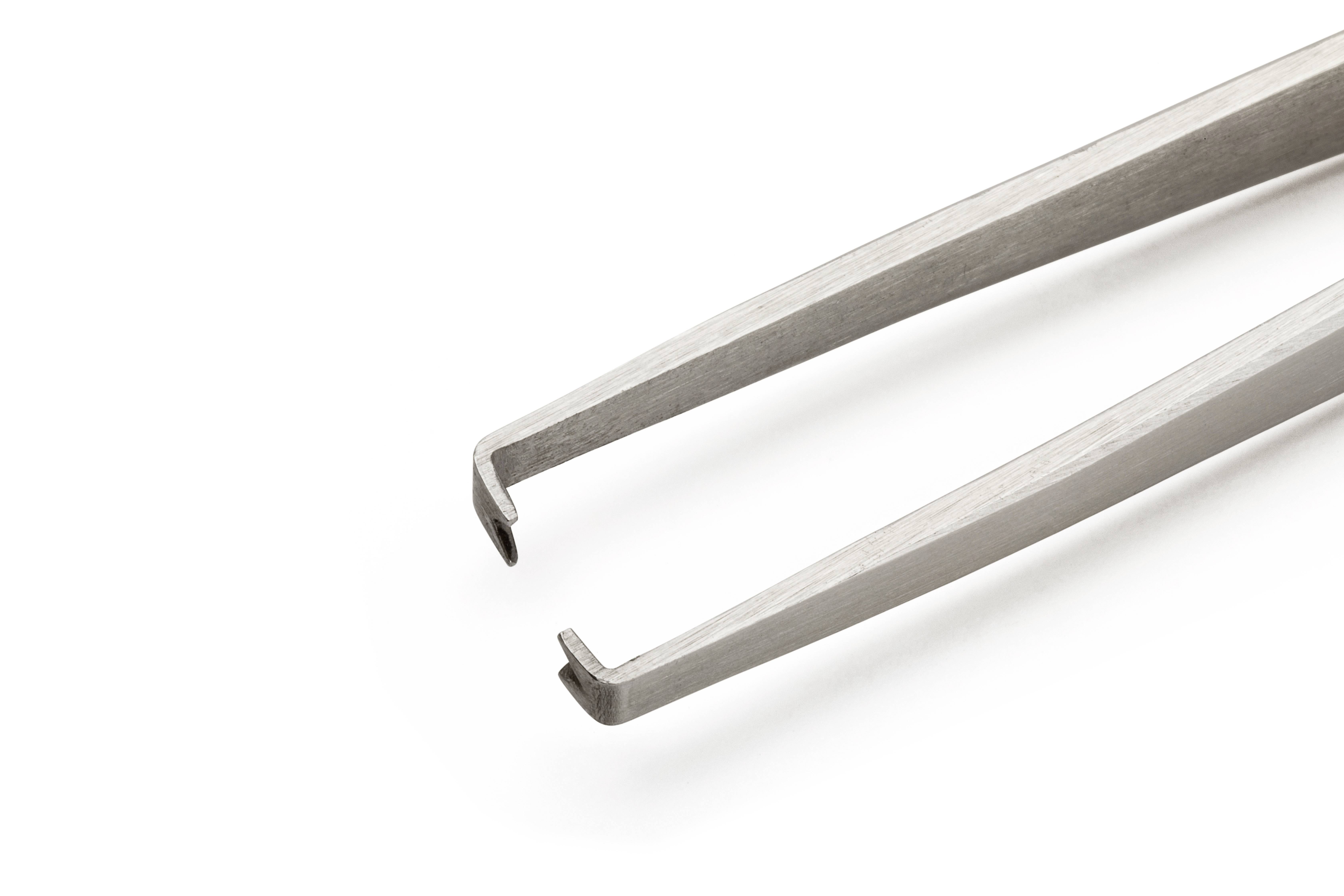 Srebrna metalowa pinceta z zaggiętymi końcówkami, odizolowana na białym tle.