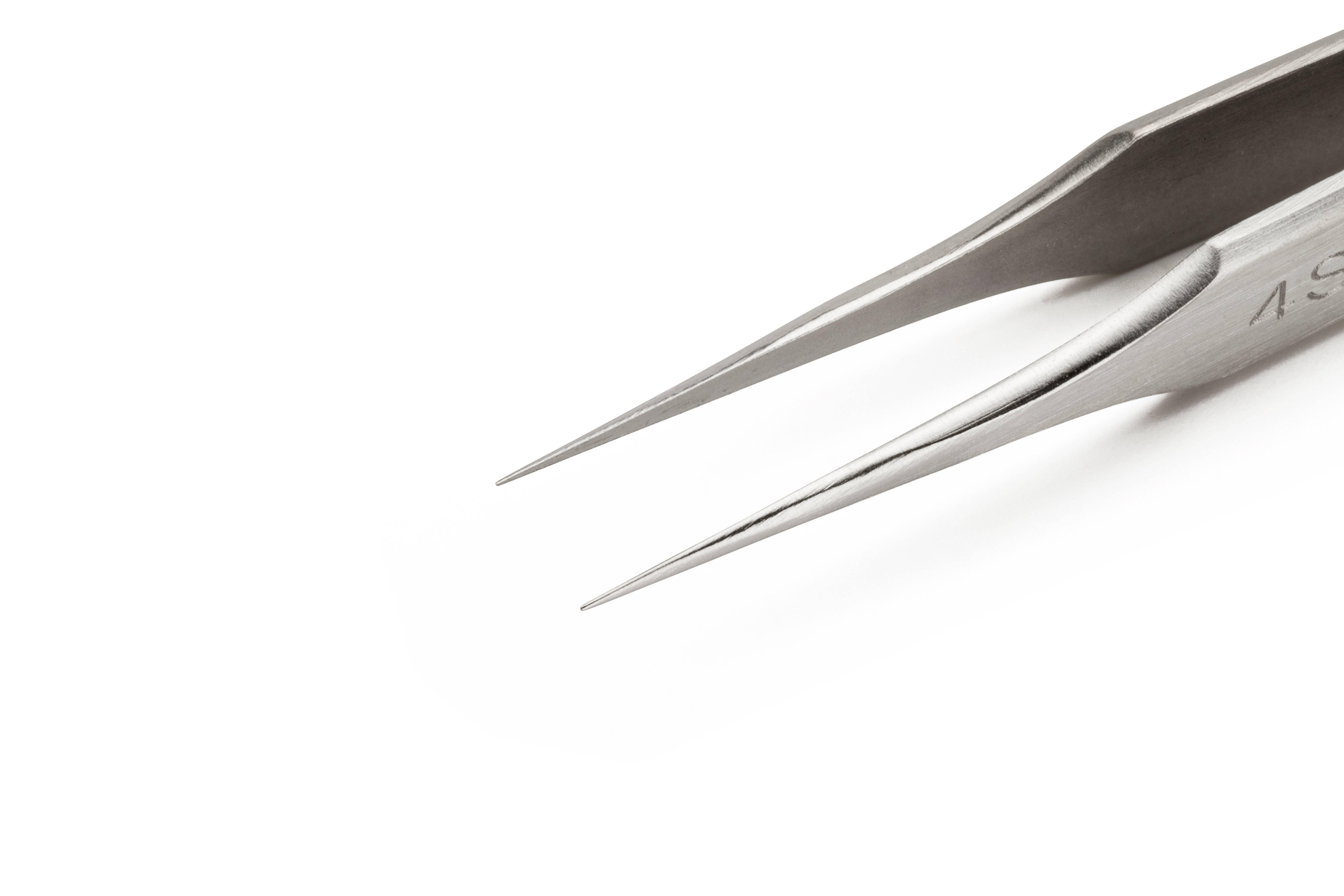 Srebrna pęseta o ostrych, zwężających się końcach leży skośnie na białym tle.