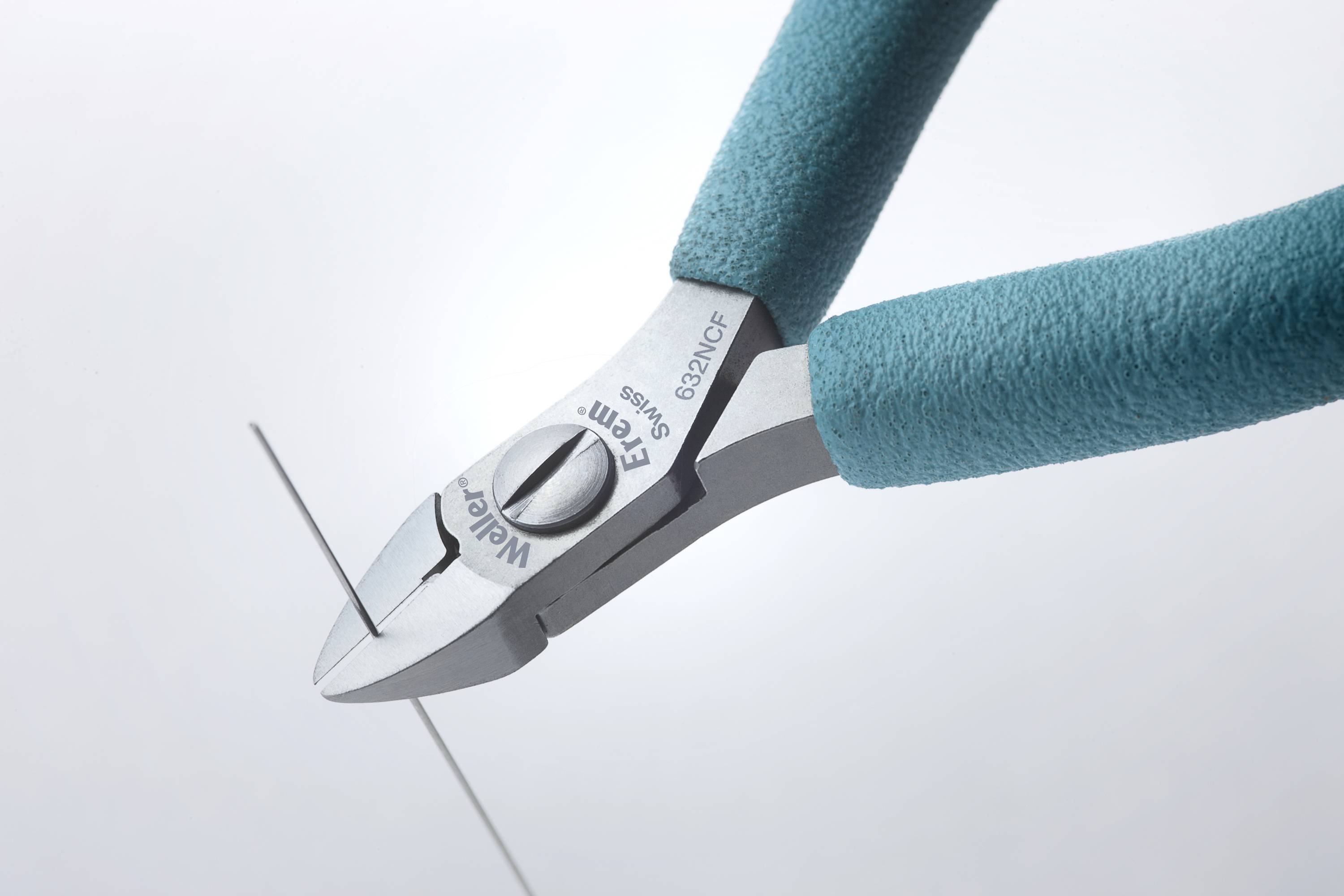 Zbliżenie szczypców do cięcia w kolorze niebieskim przecinających cienki drut.