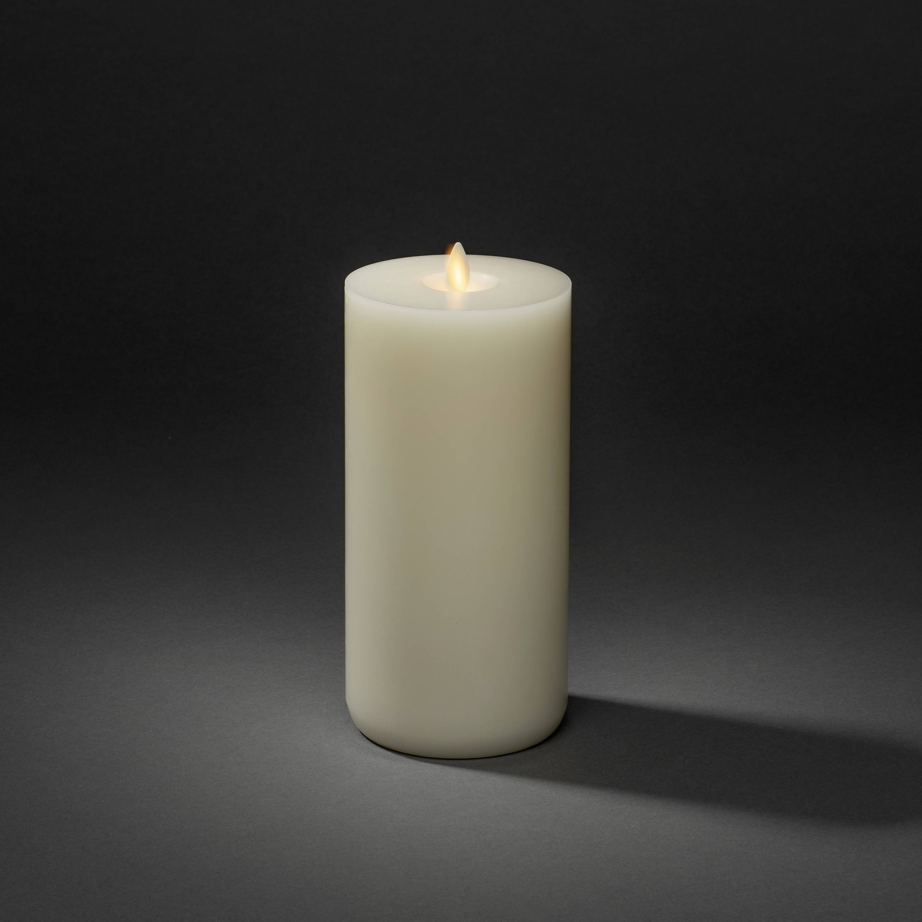 Płonąca biała świeca na ciemnym tle. Płomień delikatnie świeci i rzuca słaby cień.