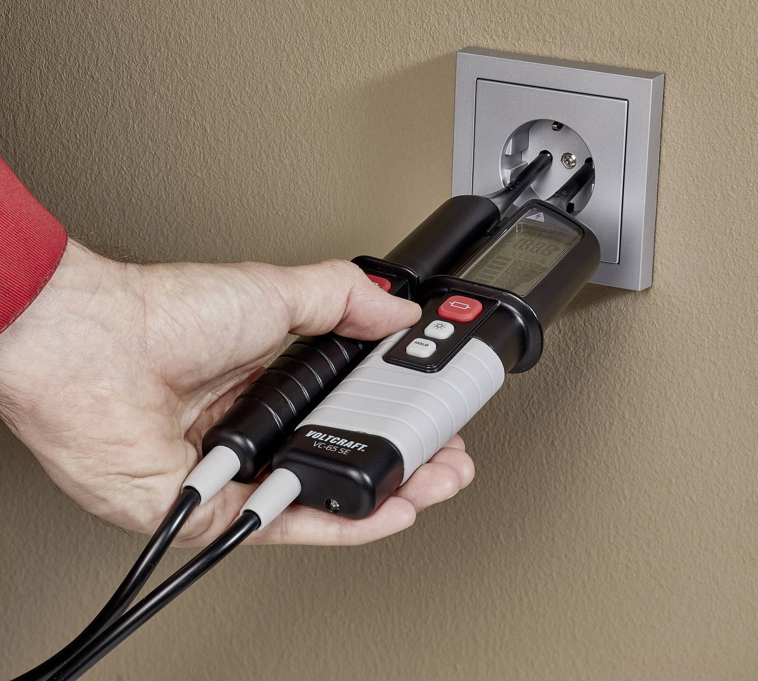 Osoba sprawdza gniazdo elektryczne za pomocą testera napięcia, wkładając sondy pomiarowe do gniazda.