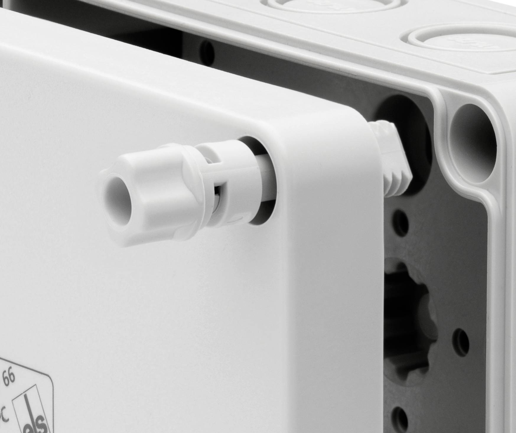 Zbliżenie białej obudowy z tworzywa sztucznego z bocznym przepustem kablowym. Odpowiednia do zastosowań w elektrotechnice.