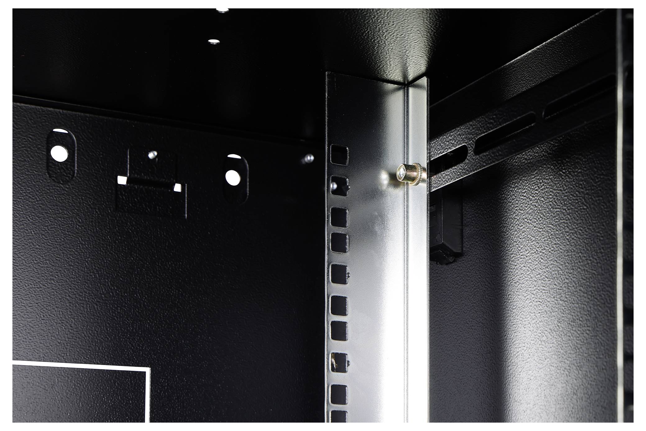 Widok wnętrza narożnika czarnej metalowej szafki, ukazujący perforowane listwy i metalowy wspornik z wkrętem w minimalistycznym stylu.