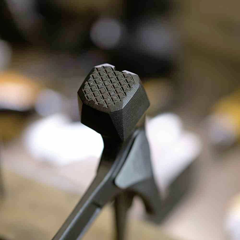 Rombowy, strukturalny odbój drzwiowy z czarnego metalu na drewnianej podłodze, z rozmytym tłem.