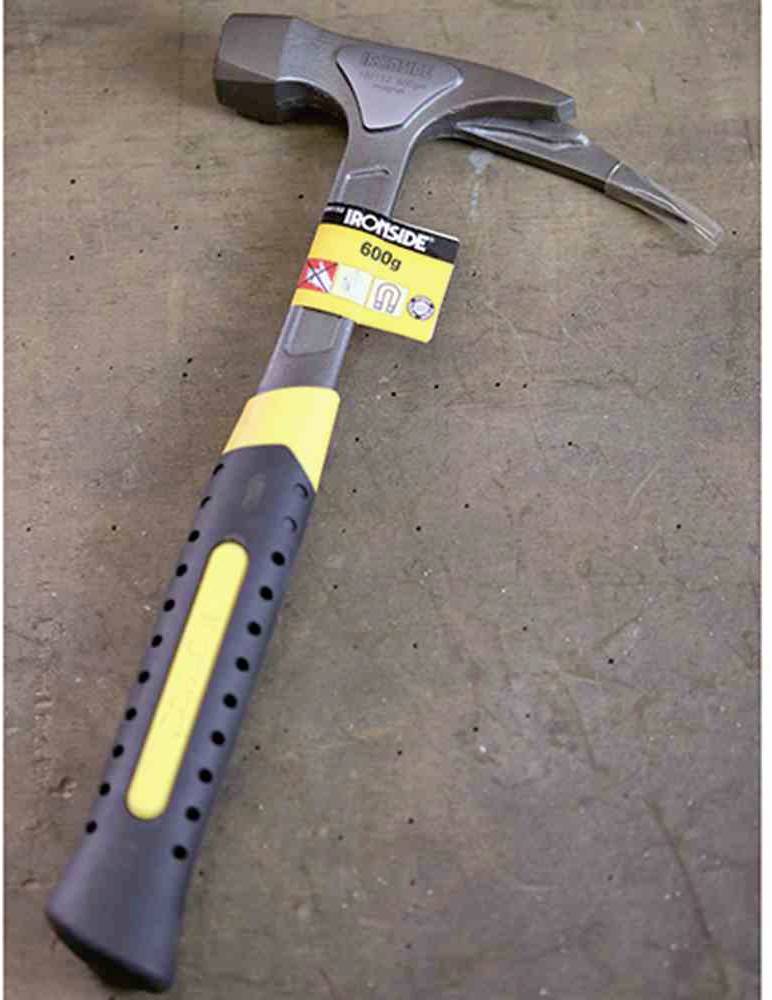 Młotek z żółto-czarnym uchwytem leży na szarej powierzchni. Na młotku znajduje się etykieta z napisem 'Ironside 600g'.